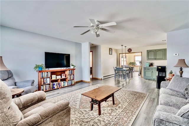 living room with baseboard heating, light wood-type flooring, a ceiling fan, and baseboards