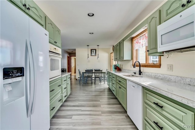 kitchen with green cabinets, white appliances, a sink, and light wood-style flooring