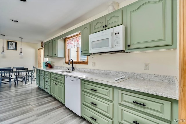 kitchen featuring white appliances, a sink, light countertops, light wood finished floors, and green cabinetry