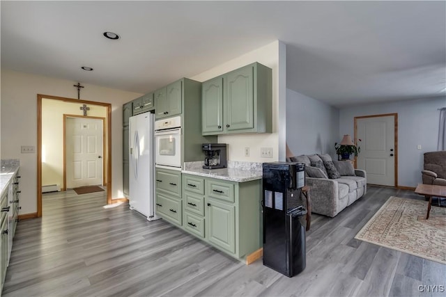 kitchen with white appliances, light wood-style flooring, open floor plan, a baseboard heating unit, and green cabinetry