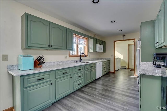 kitchen featuring white appliances, green cabinetry, a sink, and separate washer and dryer