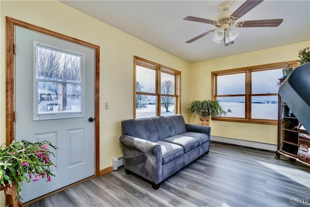 sitting room featuring baseboards, a ceiling fan, a baseboard radiator, wood finished floors, and a baseboard heating unit