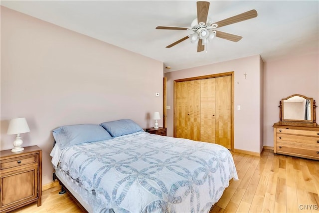 bedroom with light wood-style floors, a closet, ceiling fan, and baseboards