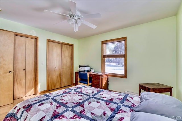 bedroom featuring ceiling fan, baseboard heating, and two closets