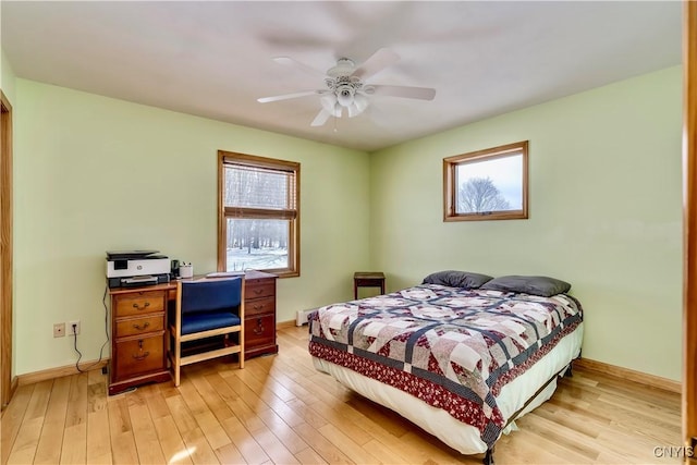 bedroom with light wood-style floors, multiple windows, baseboards, and a ceiling fan