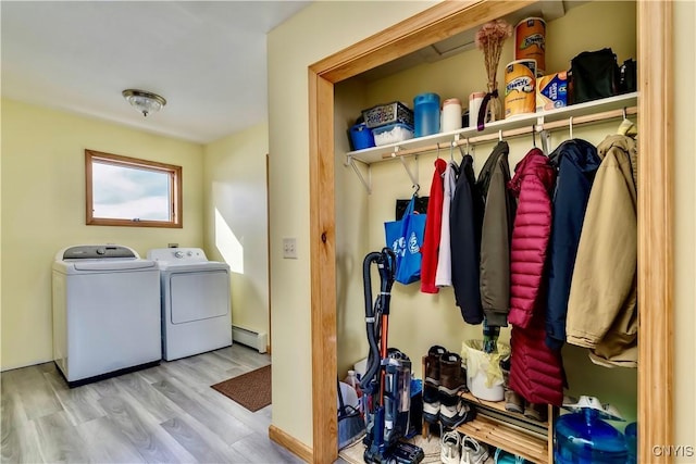 laundry area featuring laundry area, wood finished floors, a baseboard radiator, and washing machine and clothes dryer