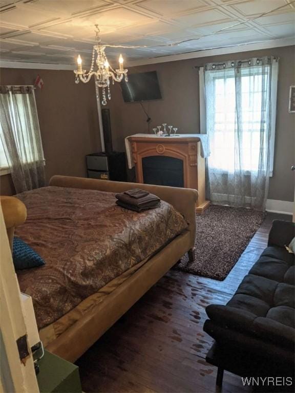 bedroom with an ornate ceiling, a fireplace, crown molding, and wood finished floors