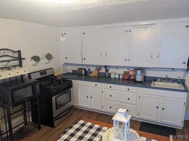 kitchen featuring dark wood-style flooring, white cabinetry, a sink, black microwave, and stainless steel gas range oven