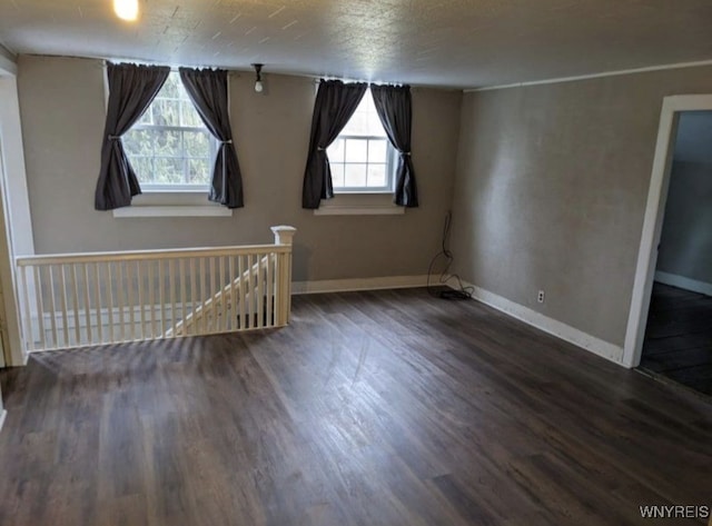 spare room featuring a textured ceiling, baseboards, and wood finished floors