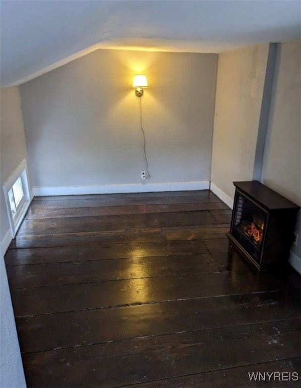 interior space with a wood stove, baseboards, dark wood-style flooring, and lofted ceiling