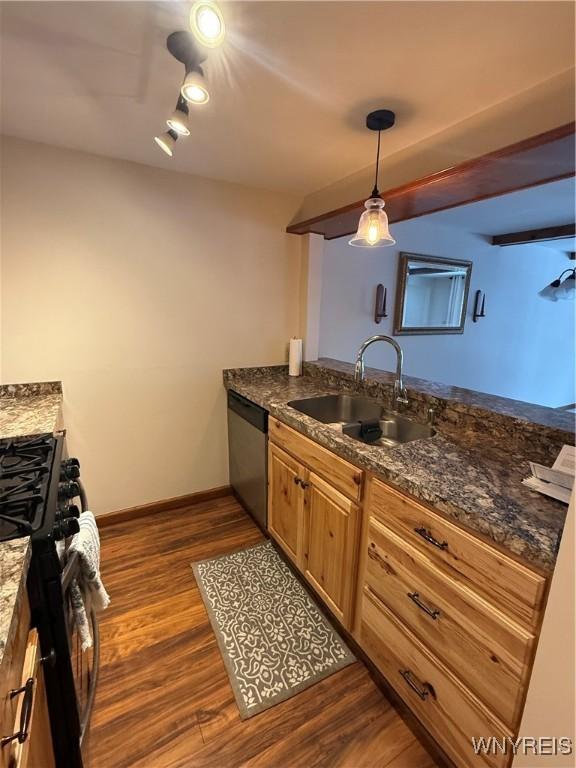 kitchen with baseboards, dark stone counters, dark wood-style floors, appliances with stainless steel finishes, and a sink