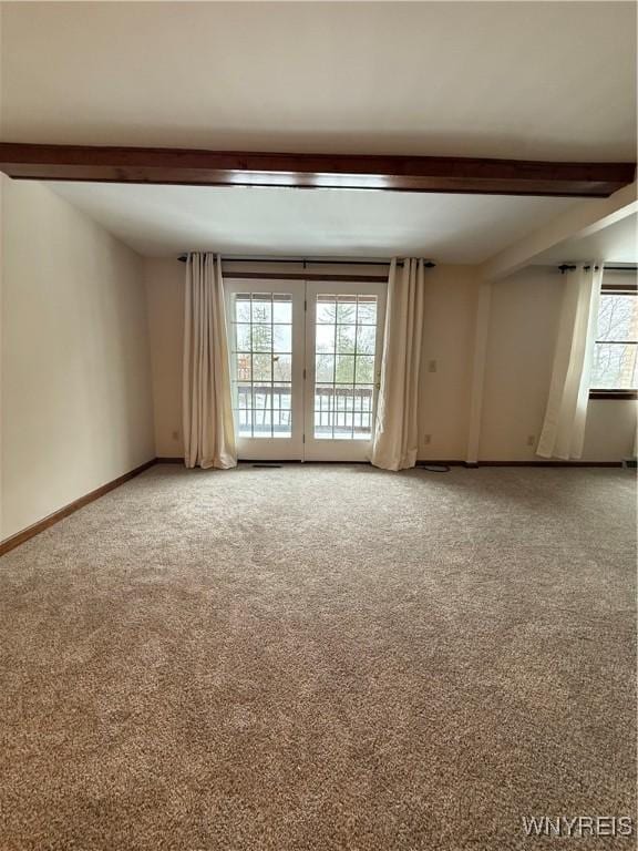 empty room with light colored carpet, beamed ceiling, and baseboards