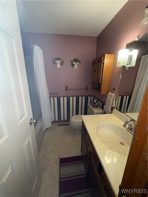 bathroom featuring toilet, shower / bathtub combination with curtain, and vanity