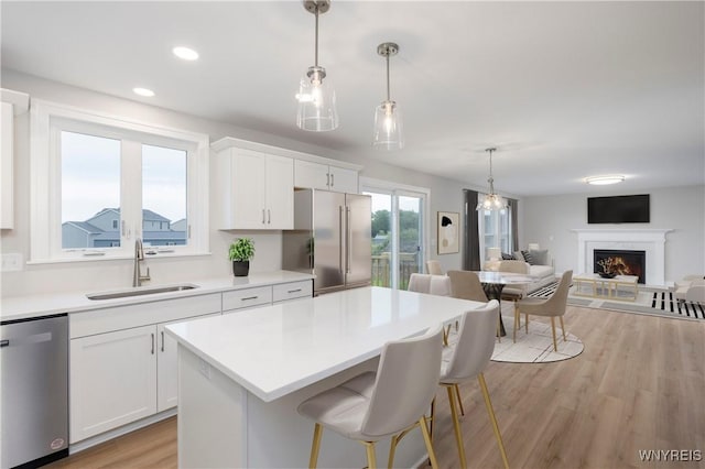 kitchen featuring light wood-type flooring, appliances with stainless steel finishes, light countertops, and a sink