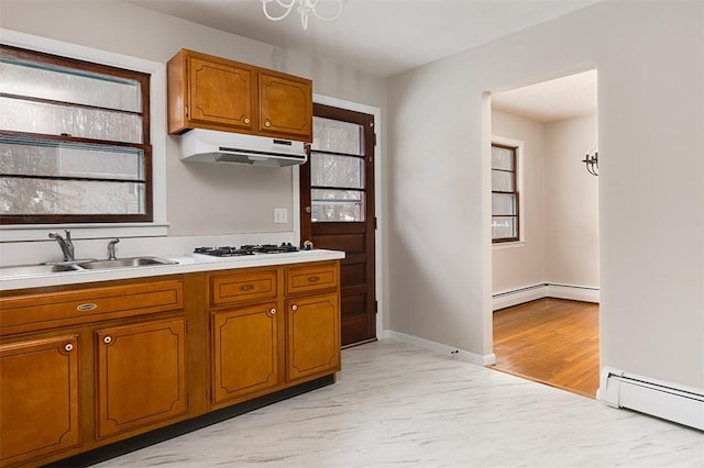 kitchen featuring a baseboard radiator, light countertops, brown cabinetry, a sink, and under cabinet range hood