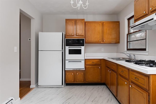 kitchen with white appliances, light countertops, under cabinet range hood, a sink, and a warming drawer