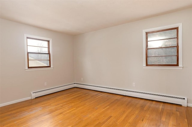 unfurnished room featuring light wood-type flooring, baseboards, and a baseboard heating unit