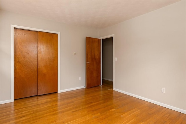 unfurnished bedroom featuring a closet, baseboards, and light wood finished floors