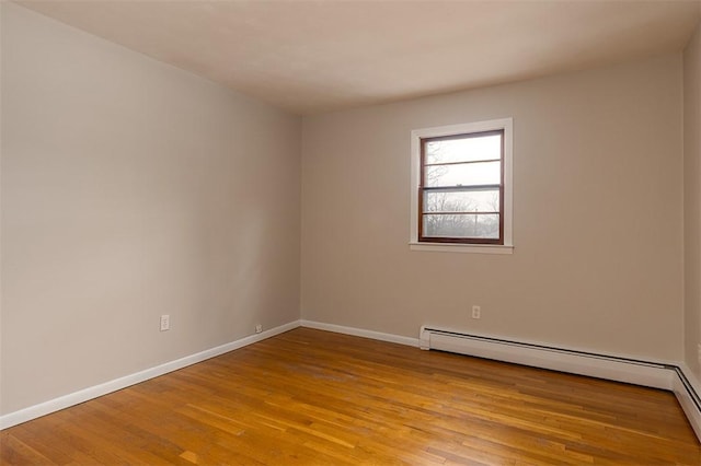 empty room with light wood-style floors, a baseboard heating unit, and baseboards