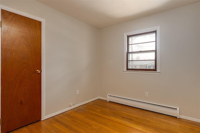 spare room with baseboards, baseboard heating, and wood finished floors