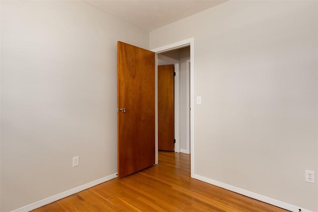 spare room with baseboards and wood finished floors