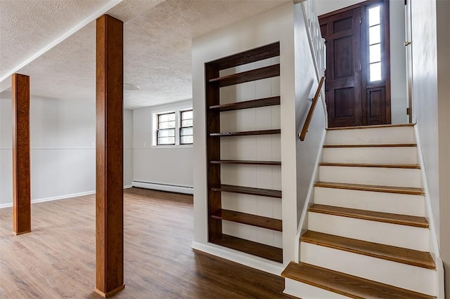 stairs with a baseboard radiator, a textured ceiling, baseboards, and wood finished floors