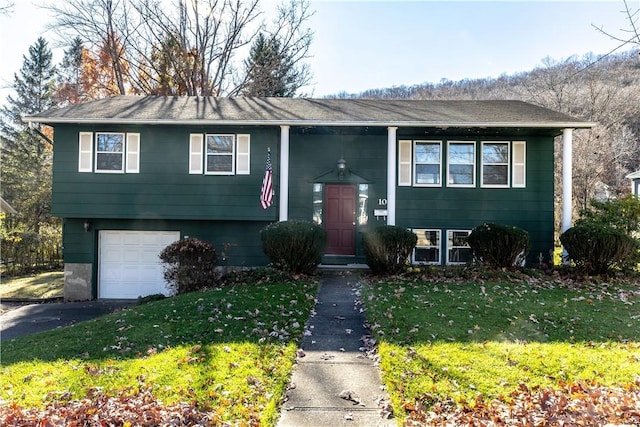 bi-level home with an attached garage, aphalt driveway, and a front yard