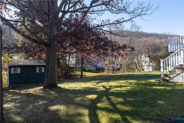 view of yard with an outbuilding, stairway, and a shed