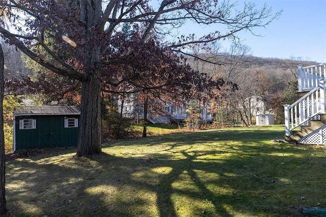 view of yard with a storage shed, stairway, and an outbuilding