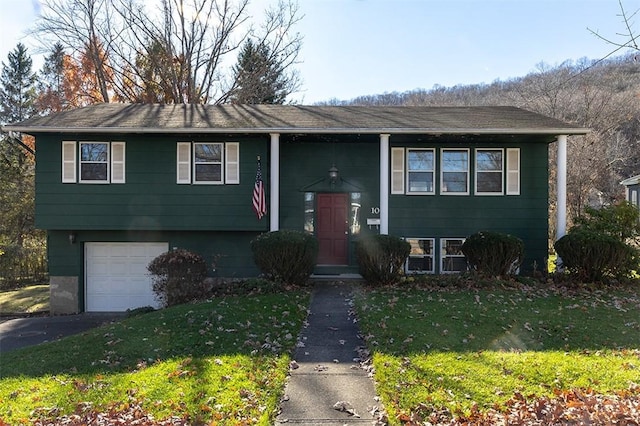 raised ranch with a garage, a front lawn, and aphalt driveway