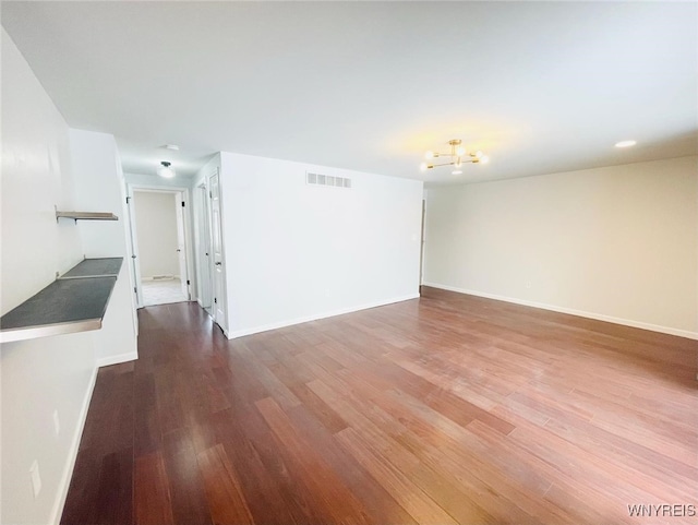 spare room featuring visible vents, baseboards, dark wood finished floors, and a chandelier