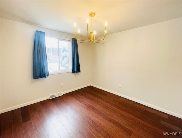 unfurnished room featuring dark wood-style flooring, visible vents, and baseboards