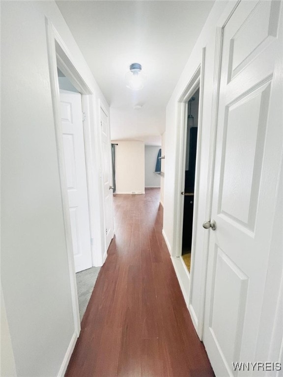 hallway featuring dark wood finished floors and baseboards