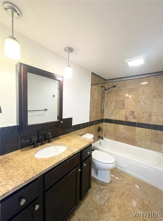 full bathroom featuring vanity, bathtub / shower combination, toilet, and tile walls