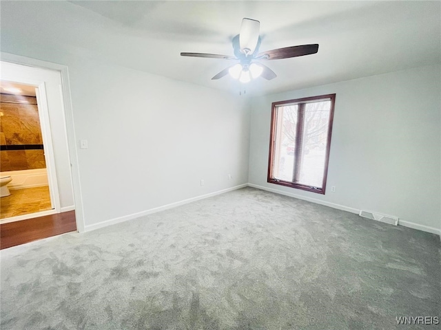 carpeted empty room with a ceiling fan, visible vents, and baseboards