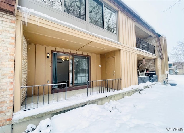 snow covered property entrance with brick siding