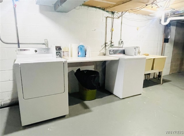 laundry area with laundry area, washing machine and dryer, and concrete block wall