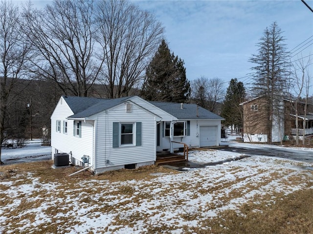 snow covered back of property featuring a garage and central air condition unit