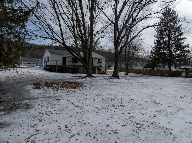 yard layered in snow featuring a garage and fence