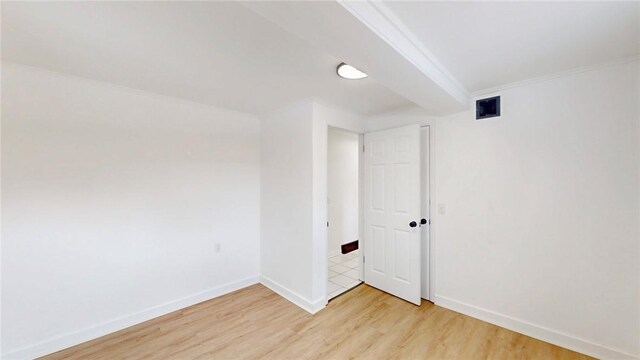 unfurnished room with ornamental molding, visible vents, light wood-style flooring, and baseboards