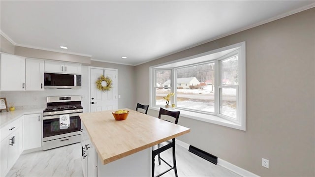 kitchen featuring stainless steel appliances, white cabinets, crown molding, and baseboards