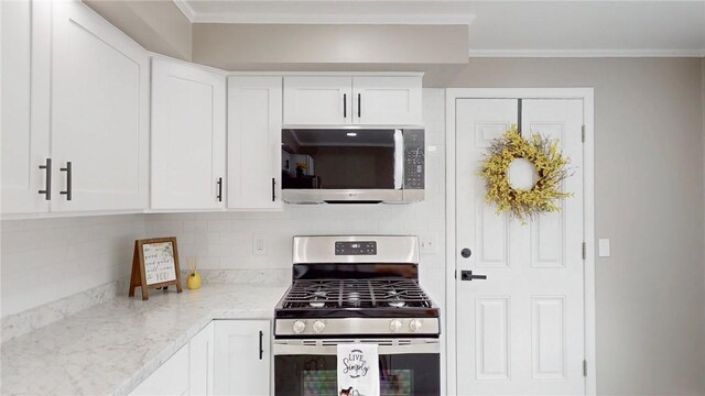 kitchen featuring light stone counters, decorative backsplash, appliances with stainless steel finishes, ornamental molding, and white cabinets