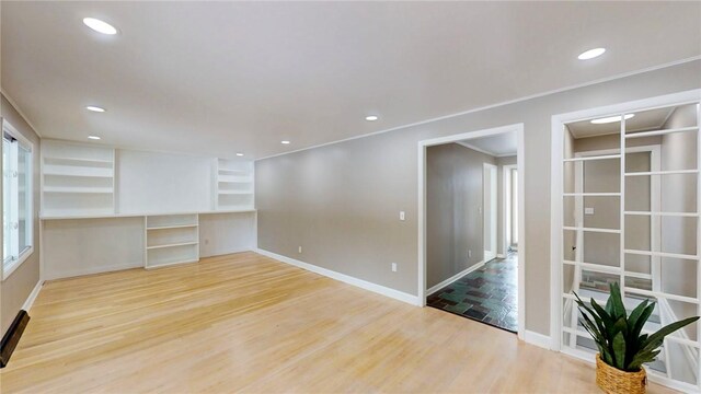 empty room featuring recessed lighting, crown molding, baseboards, and wood finished floors