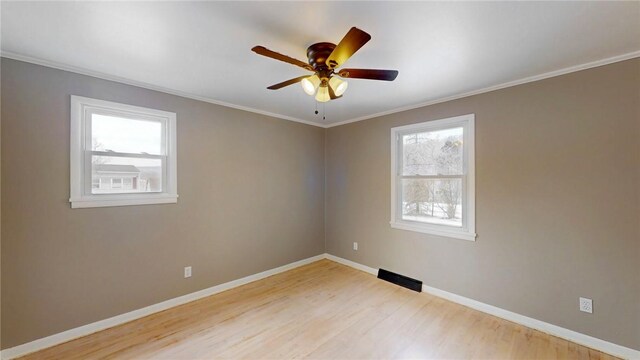 spare room featuring crown molding, baseboards, and wood finished floors