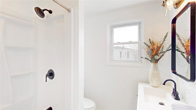 bathroom featuring toilet, walk in shower, and a sink