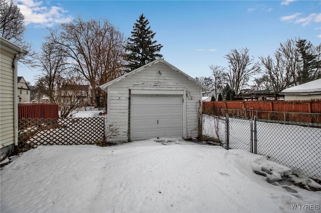 snow covered garage with a garage and fence