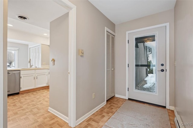 doorway to outside featuring brick floor, visible vents, a sink, and baseboards