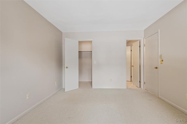 unfurnished bedroom with a spacious closet, baseboards, and light colored carpet