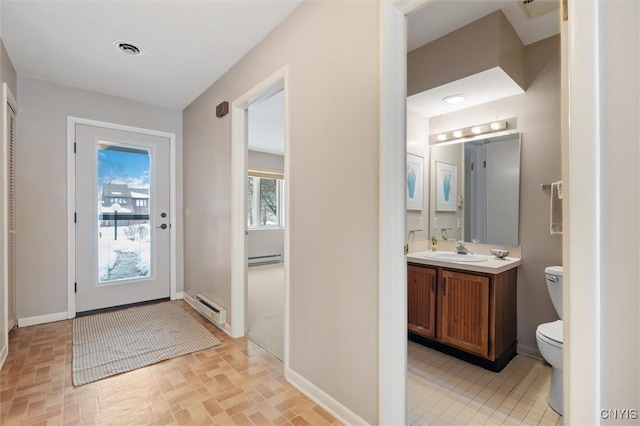 doorway to outside featuring a baseboard radiator, visible vents, a sink, and baseboards