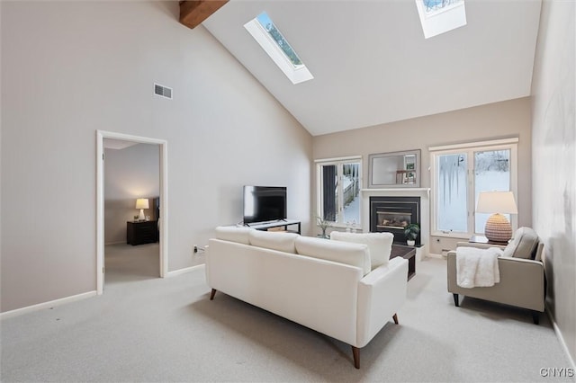 living area with light colored carpet, visible vents, a glass covered fireplace, high vaulted ceiling, and beamed ceiling